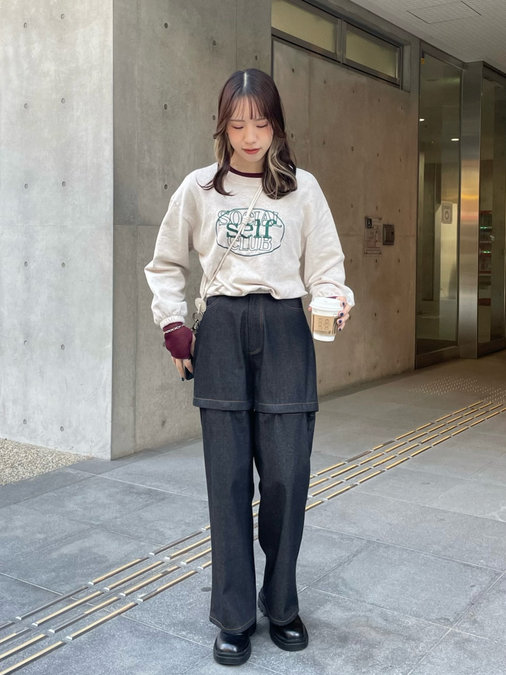 ブラック系のデニムパンツ、ブラック系のブーツ、ベージュ系のスウェットを着用したレディースの冬コーディネートの2枚目の写真