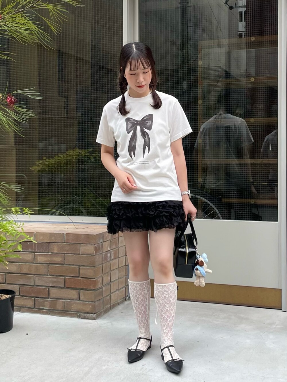 ホワイト系のTシャツ/カットソー、ブラック系のパンプス、ブラック系のハンドバッグを着用したレディースの夏コーディネートの2枚目の写真