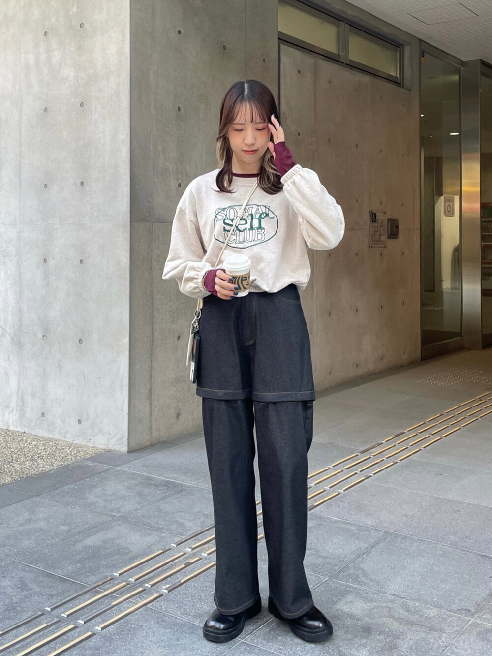 ブラック系のデニムパンツ、ブラック系のブーツ、ベージュ系のスウェットを着用したレディースの冬コーディネートの3枚目の写真