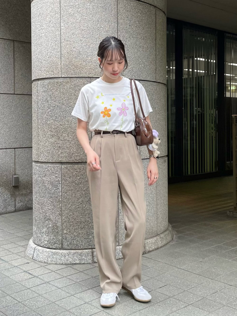 ブラウン系のショルダーバッグ、ホワイト系のTシャツ/カットソー、ベージュ系のスラックスを着用したレディースの夏コーディネートの2枚目の写真