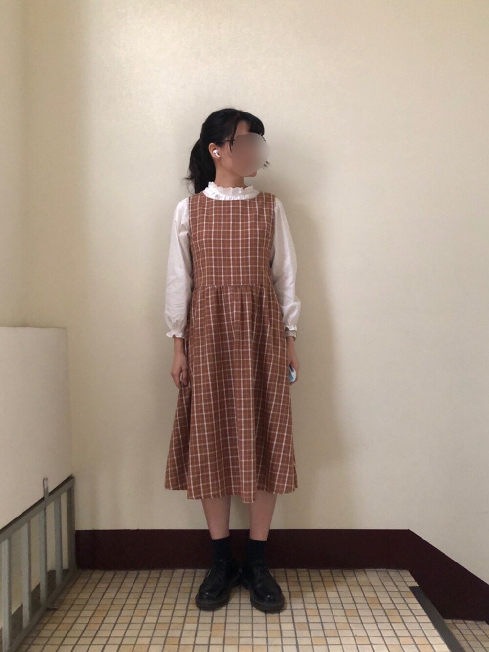 ブラウン系のジャンパースカート、ブラック系のブーツ、ホワイト系のトップスを着用したレディースの春コーディネートの2枚目の写真