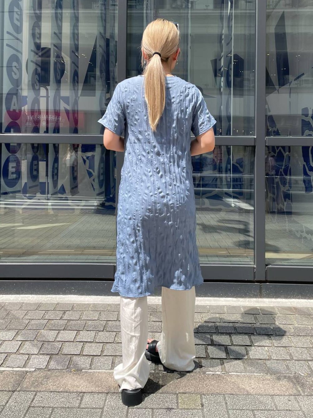 ブルー系のワンピース、ベージュ系のスラックス、グレー系のサングラスを着用したレディースの夏コーディネートの3枚目の写真