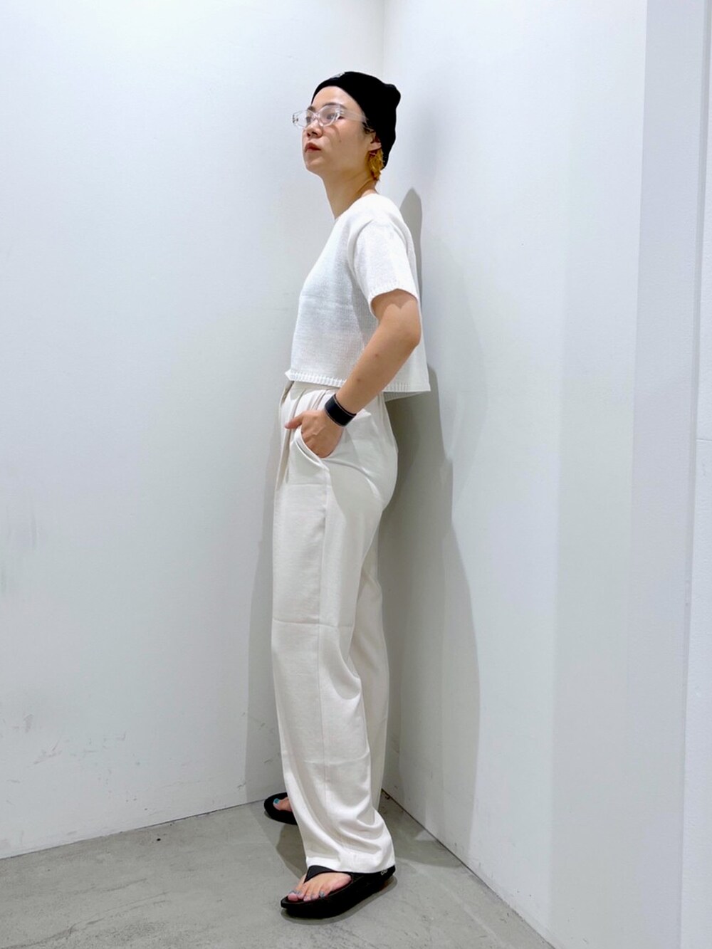 ホワイト系のニット/セーター、ベージュ系のスラックス、ブラック系のニットキャップ/ビーニーを着用したレディースの夏コーディネートの2枚目の写真