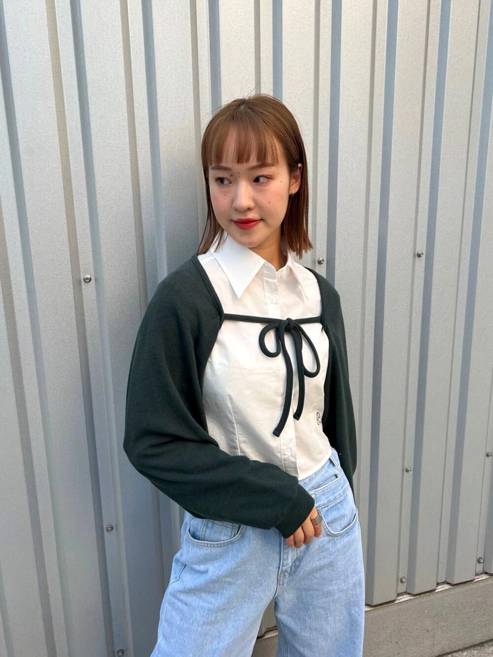 グリーン系のカーディガン/ボレロ、ベージュ系のシャツ/ブラウス、ブルー系のデニムパンツを着用したレディースの秋コーディネートの2枚目の写真