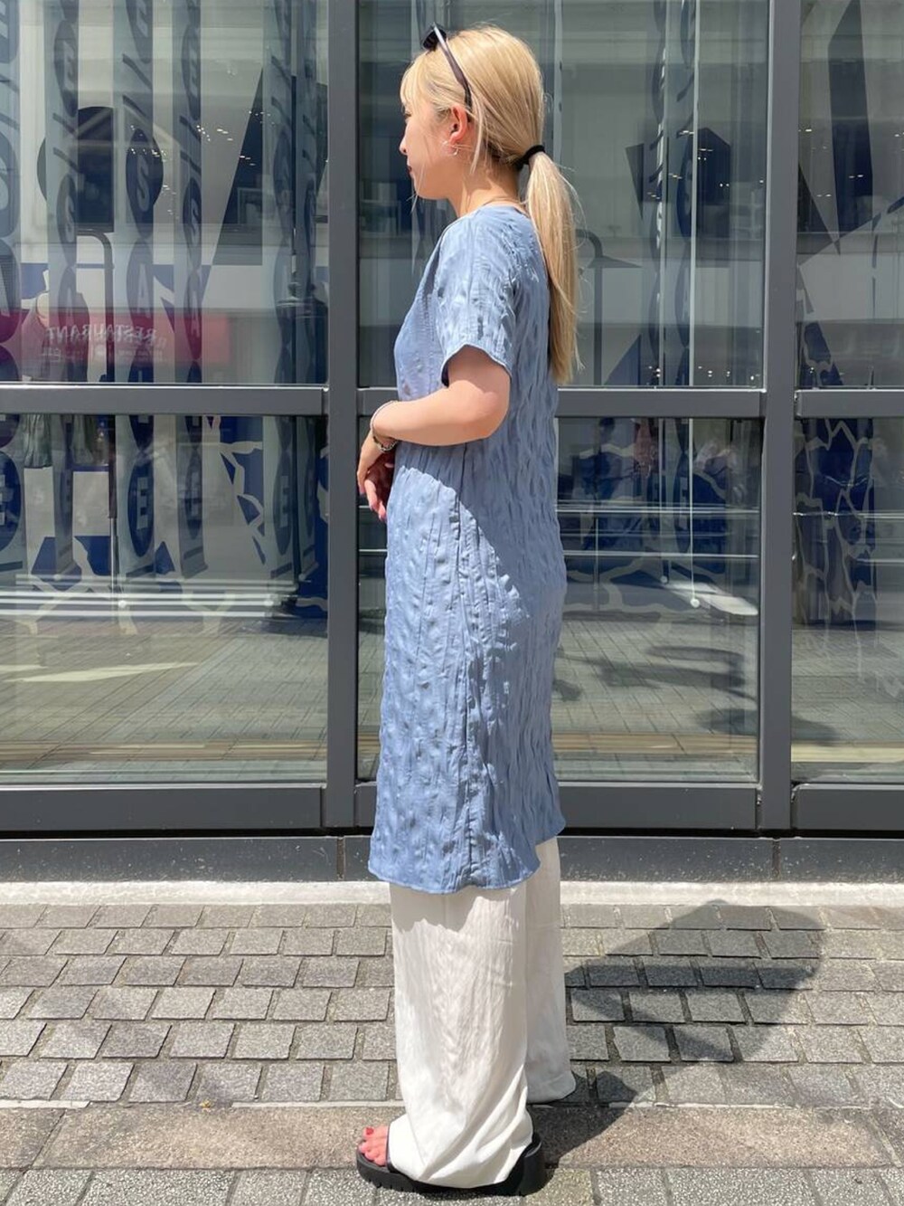 ブルー系のワンピース、ベージュ系のスラックス、グレー系のサングラスを着用したレディースの夏コーディネートの2枚目の写真