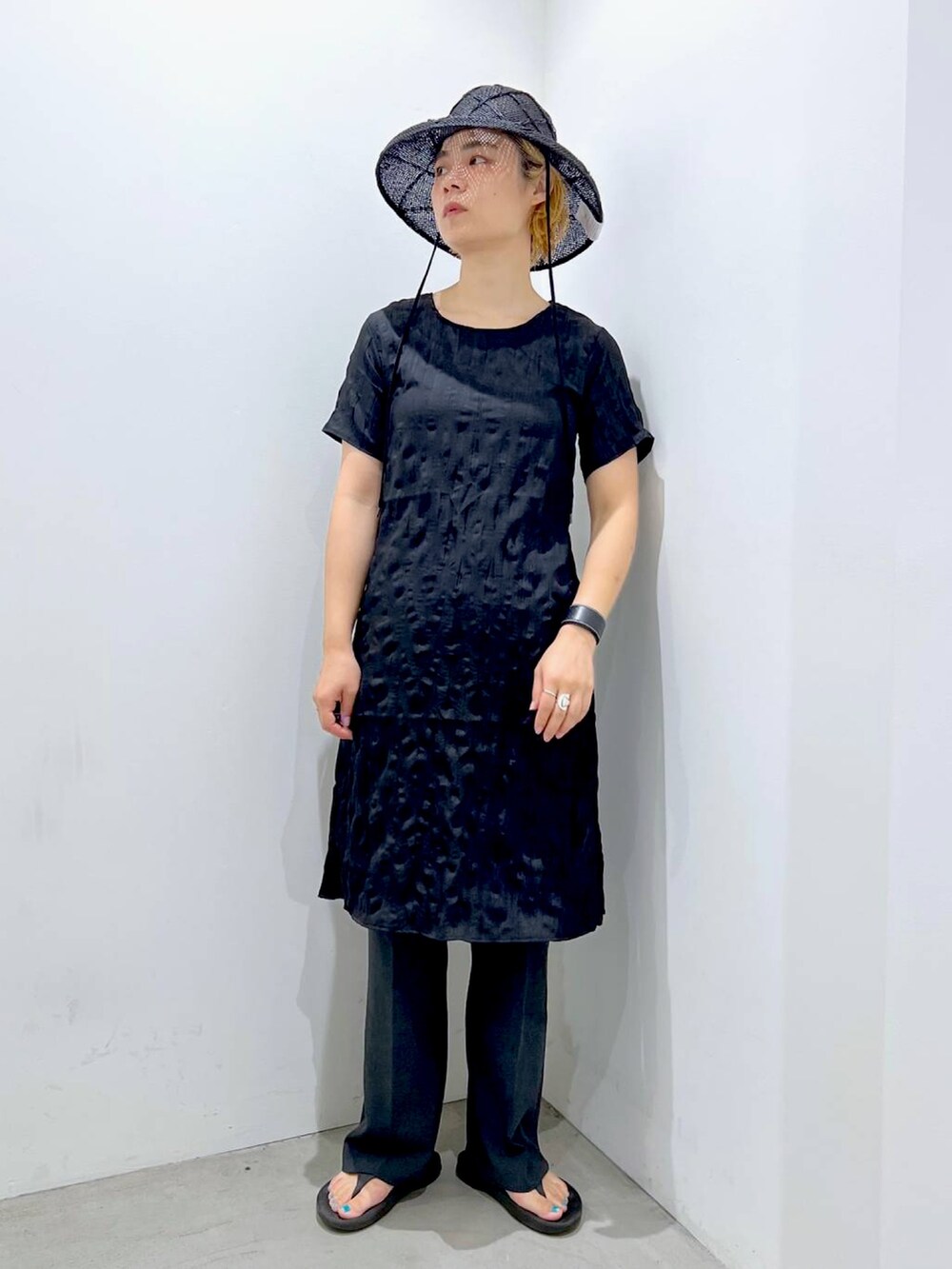 ブラック系のワンピース、グレー系のスラックスを着用したレディースの夏コーディネートの2枚目の写真