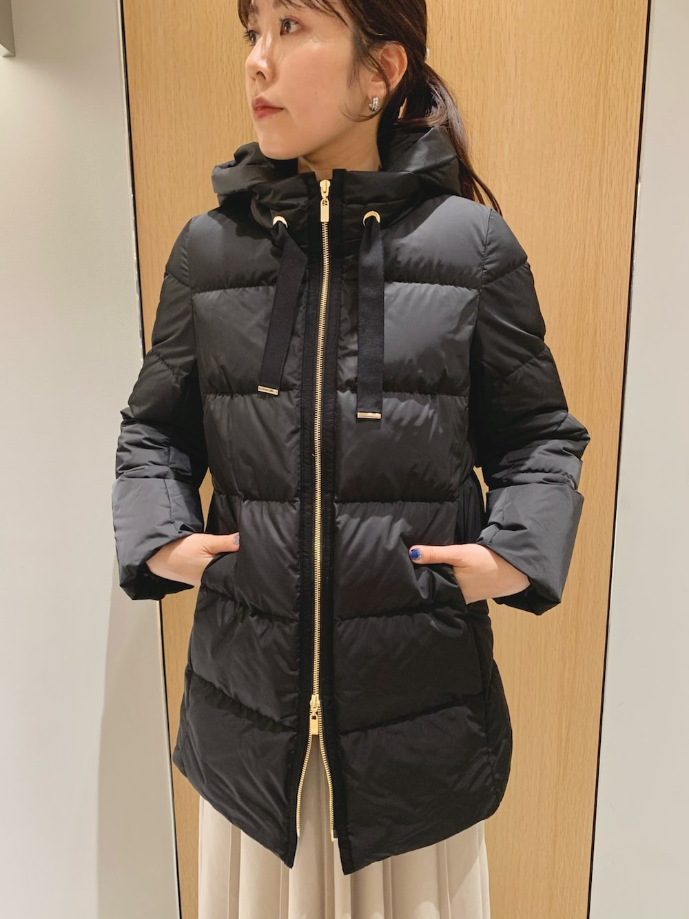 ホワイト系のスカート、ブラック系のダウンジャケット/コート、ブラック系のカーディガン/ボレロを着用したレディースの冬コーディネートの4枚目の写真