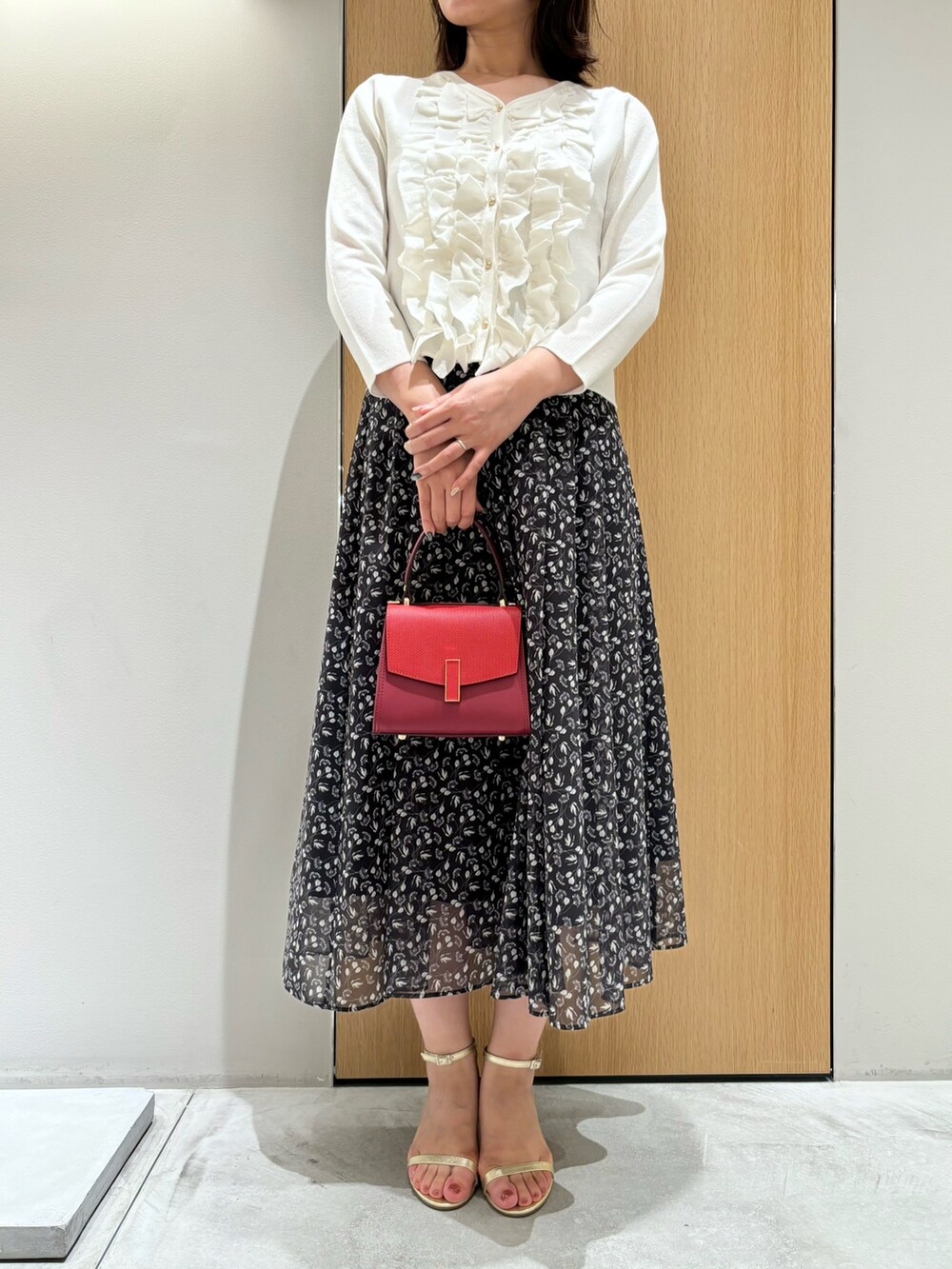 ブラック系のスカート、レッド系のハンドバッグ、ホワイト系のニット/セーターを着用したレディースの秋コーディネートの4枚目の写真