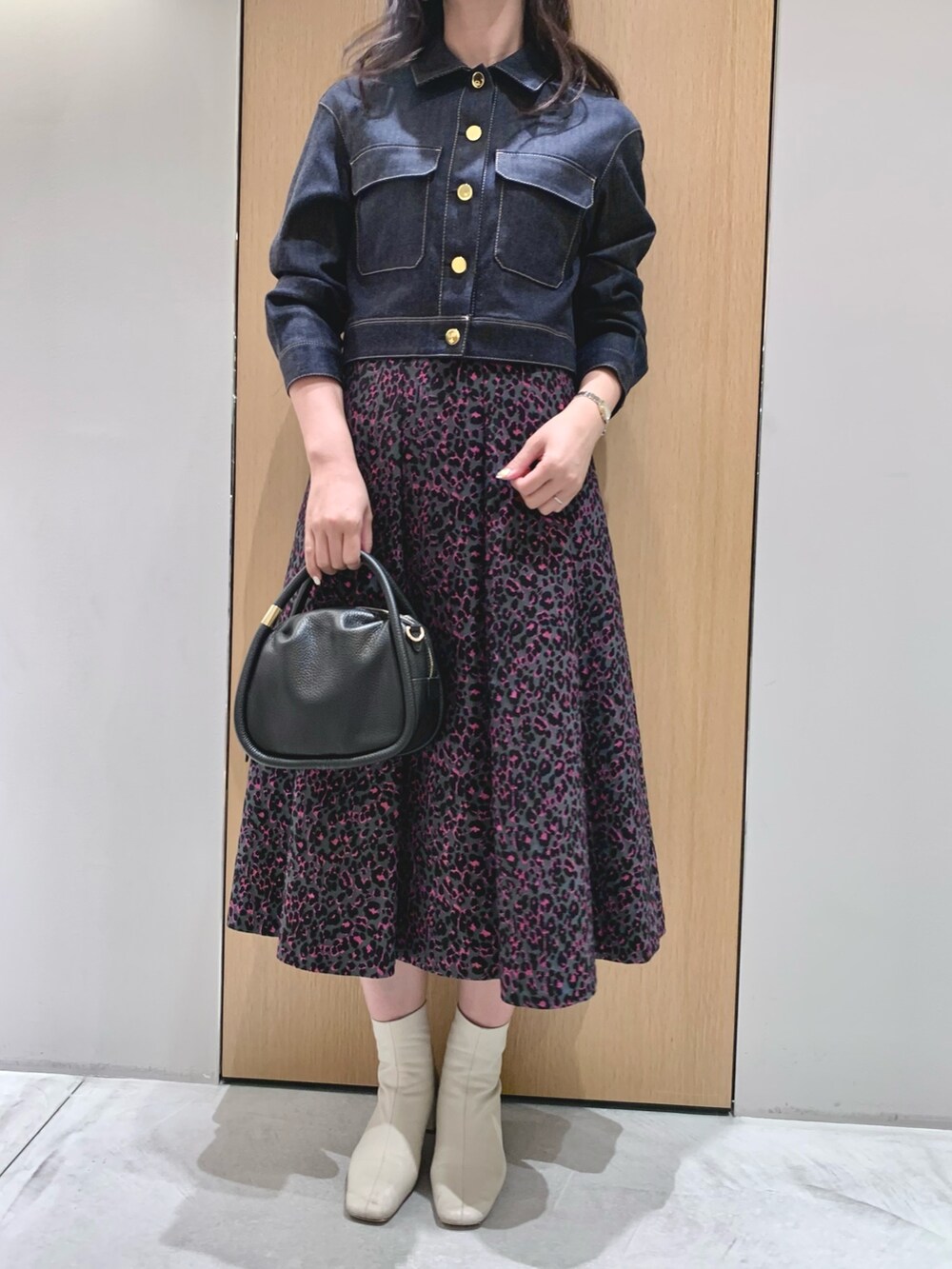 ピンク系のスカート、ブルー系のデニムジャケット、ブラック系のハンドバッグを着用したレディースの秋コーディネートの4枚目の写真