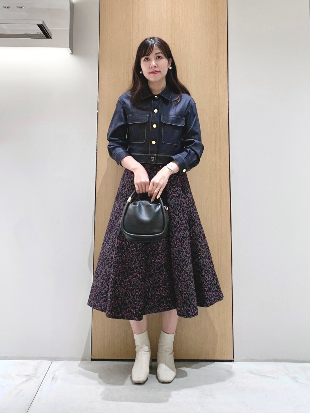 ピンク系のスカート、ブルー系のデニムジャケット、ブラック系のハンドバッグを着用したレディースの秋コーディネートの2枚目の写真