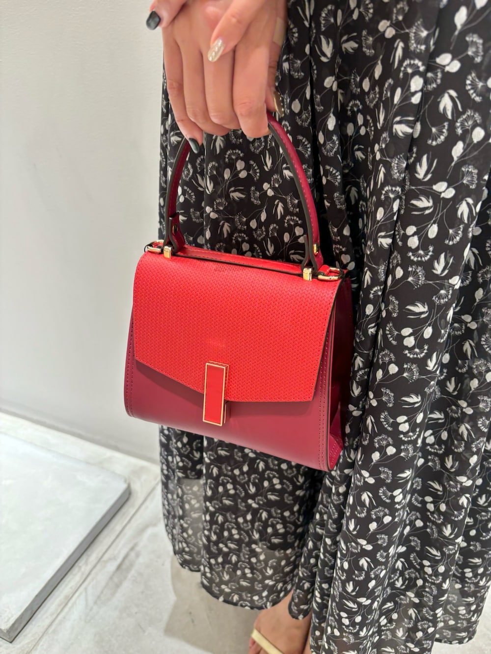 ブラック系のスカート、レッド系のハンドバッグ、ホワイト系のニット/セーターを着用したレディースの秋コーディネートの5枚目の写真