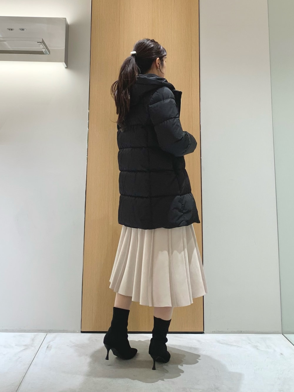 ホワイト系のスカート、ブラック系のダウンジャケット/コート、ブラック系のカーディガン/ボレロを着用したレディースの冬コーディネートの2枚目の写真