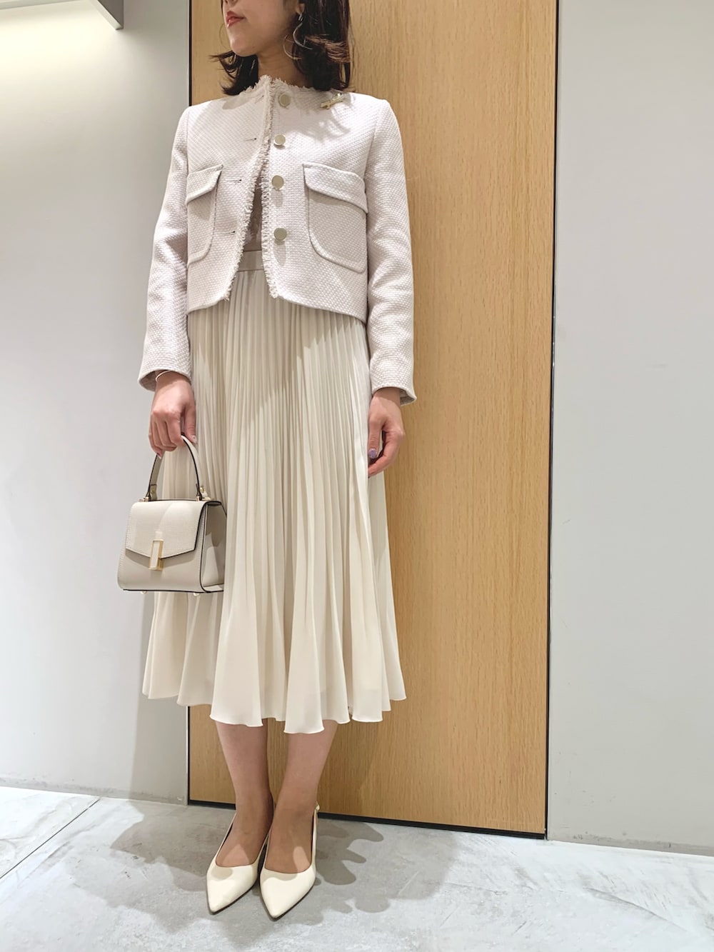 ホワイト系のスカート、ベージュ系のトートバッグ、ベージュ系のノーカラージャケットを着用したレディースの春コーディネートの3枚目の写真