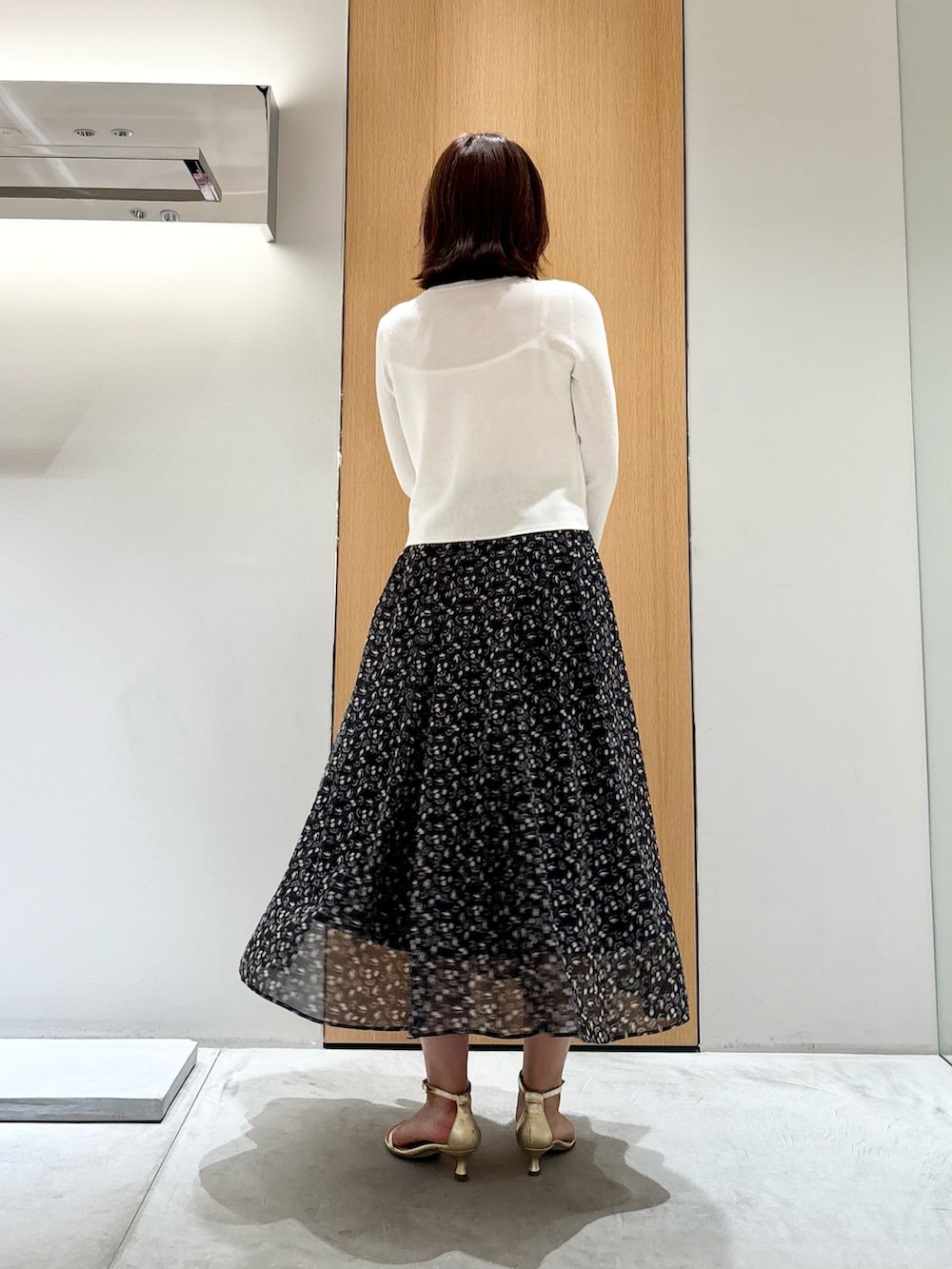 ブラック系のスカート、レッド系のハンドバッグ、ホワイト系のニット/セーターを着用したレディースの秋コーディネートの3枚目の写真