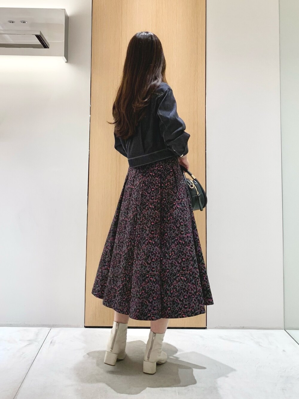 ピンク系のスカート、ブルー系のデニムジャケット、ブラック系のハンドバッグを着用したレディースの秋コーディネートの3枚目の写真