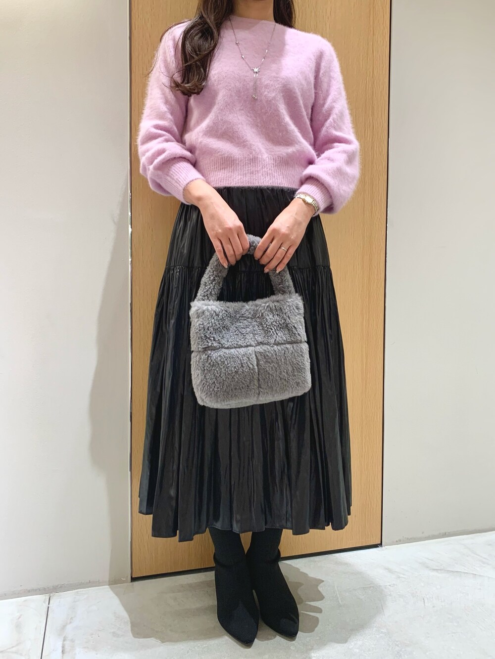 グレー系のハンドバッグ、ブラック系のスカート、パープル系のニット/セーターを着用したレディースの冬コーディネートの4枚目の写真