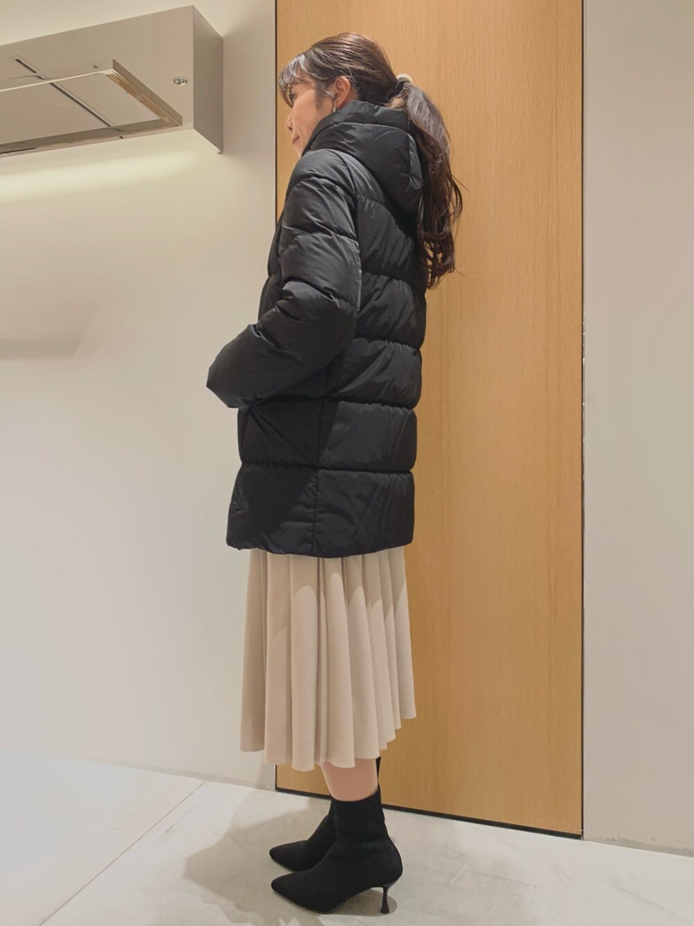 ホワイト系のスカート、ブラック系のダウンジャケット/コート、ブラック系のカーディガン/ボレロを着用したレディースの冬コーディネートの6枚目の写真