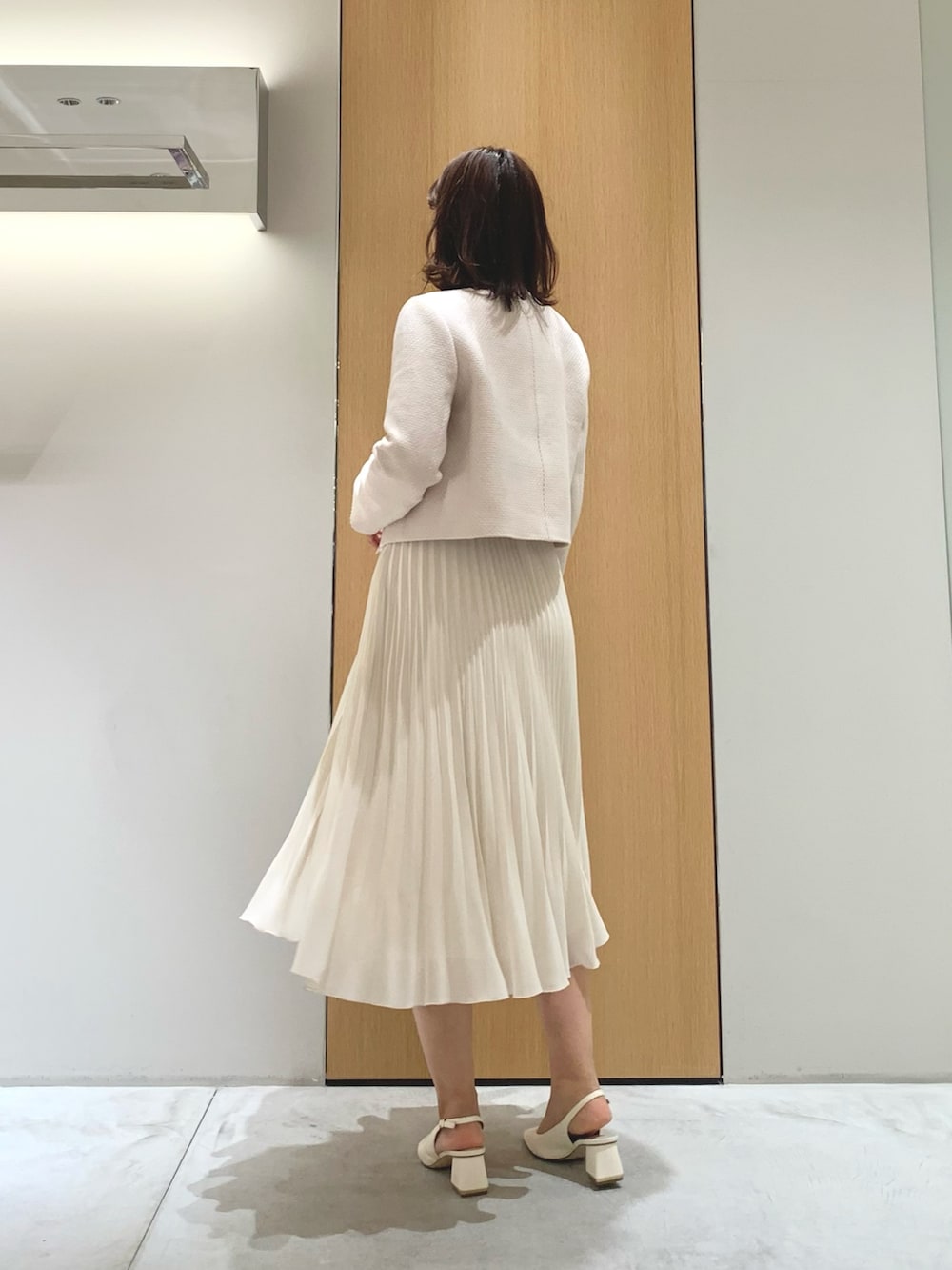 ホワイト系のスカート、ベージュ系のトートバッグ、ベージュ系のノーカラージャケットを着用したレディースの春コーディネートの2枚目の写真