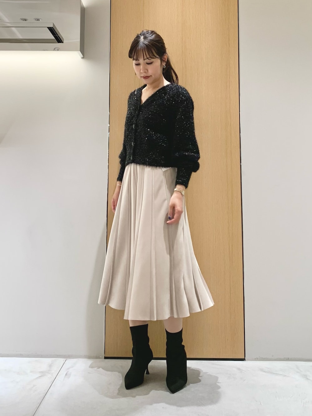 ホワイト系のスカート、ブラック系のダウンジャケット/コート、ブラック系のカーディガン/ボレロを着用したレディースの冬コーディネートの5枚目の写真