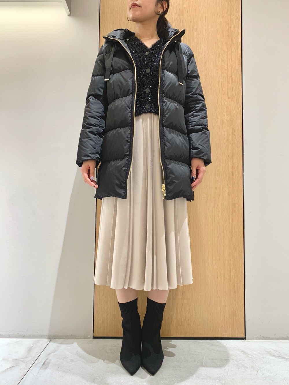 ホワイト系のスカート、ブラック系のダウンジャケット/コート、ブラック系のカーディガン/ボレロを着用したレディースの冬コーディネートの3枚目の写真