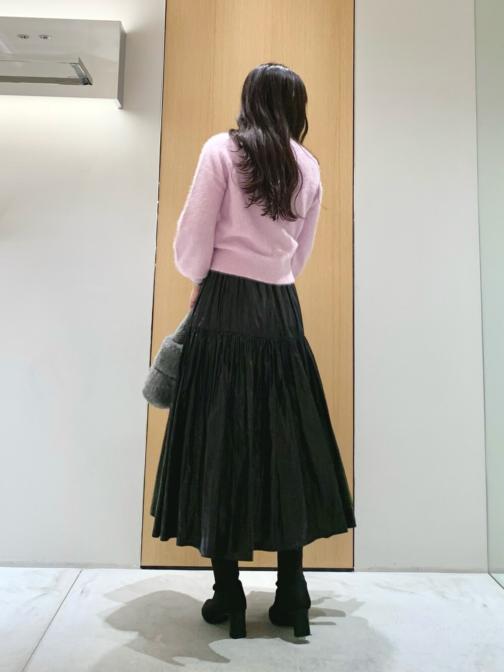 グレー系のハンドバッグ、ブラック系のスカート、パープル系のニット/セーターを着用したレディースの冬コーディネートの3枚目の写真