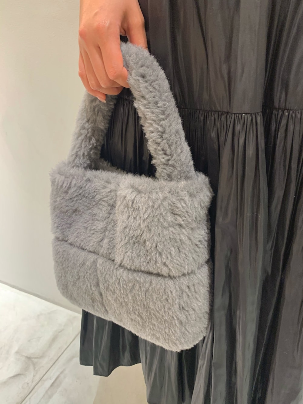 グレー系のハンドバッグ、ブラック系のスカート、パープル系のニット/セーターを着用したレディースの冬コーディネートの8枚目の写真