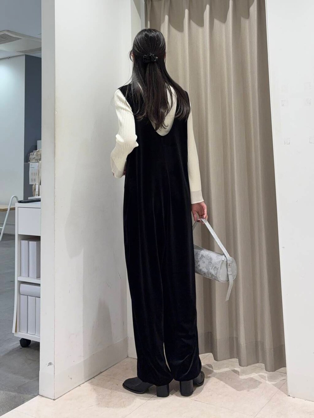 ブラック系のブーツ、ベージュ系のニット/セーター、グレー系のハンドバッグを着用したレディースの冬コーディネートの2枚目の写真