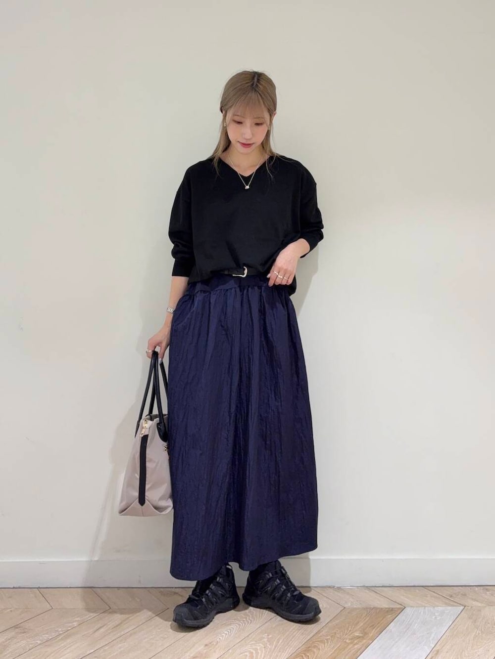 グレー系のトートバッグ、ブルー系のスカート、ブラック系のニット/セーターを着用したレディースの秋コーディネートの2枚目の写真