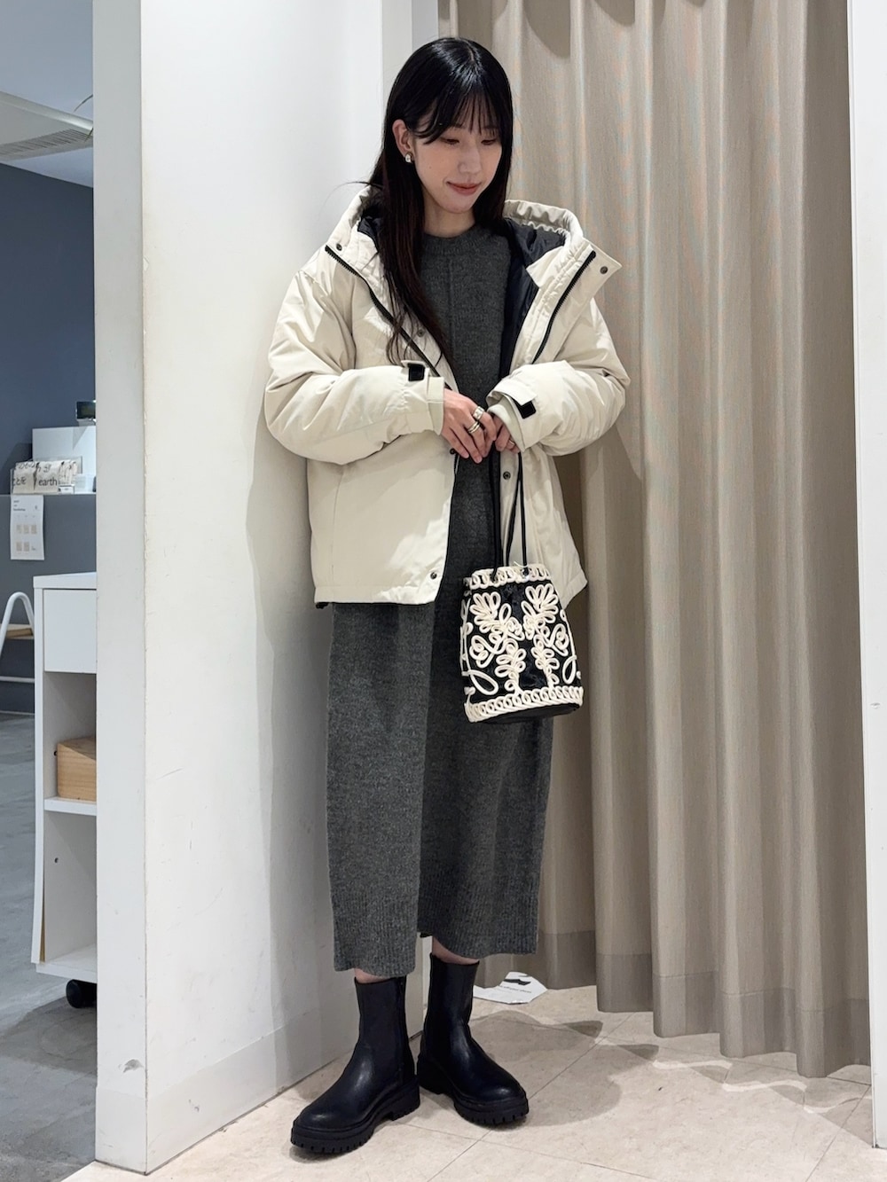 ホワイト系のダウンジャケット/コート、グレー系のワンピース、ブラック系のハンドバッグを着用したレディースの冬コーディネートの2枚目の写真