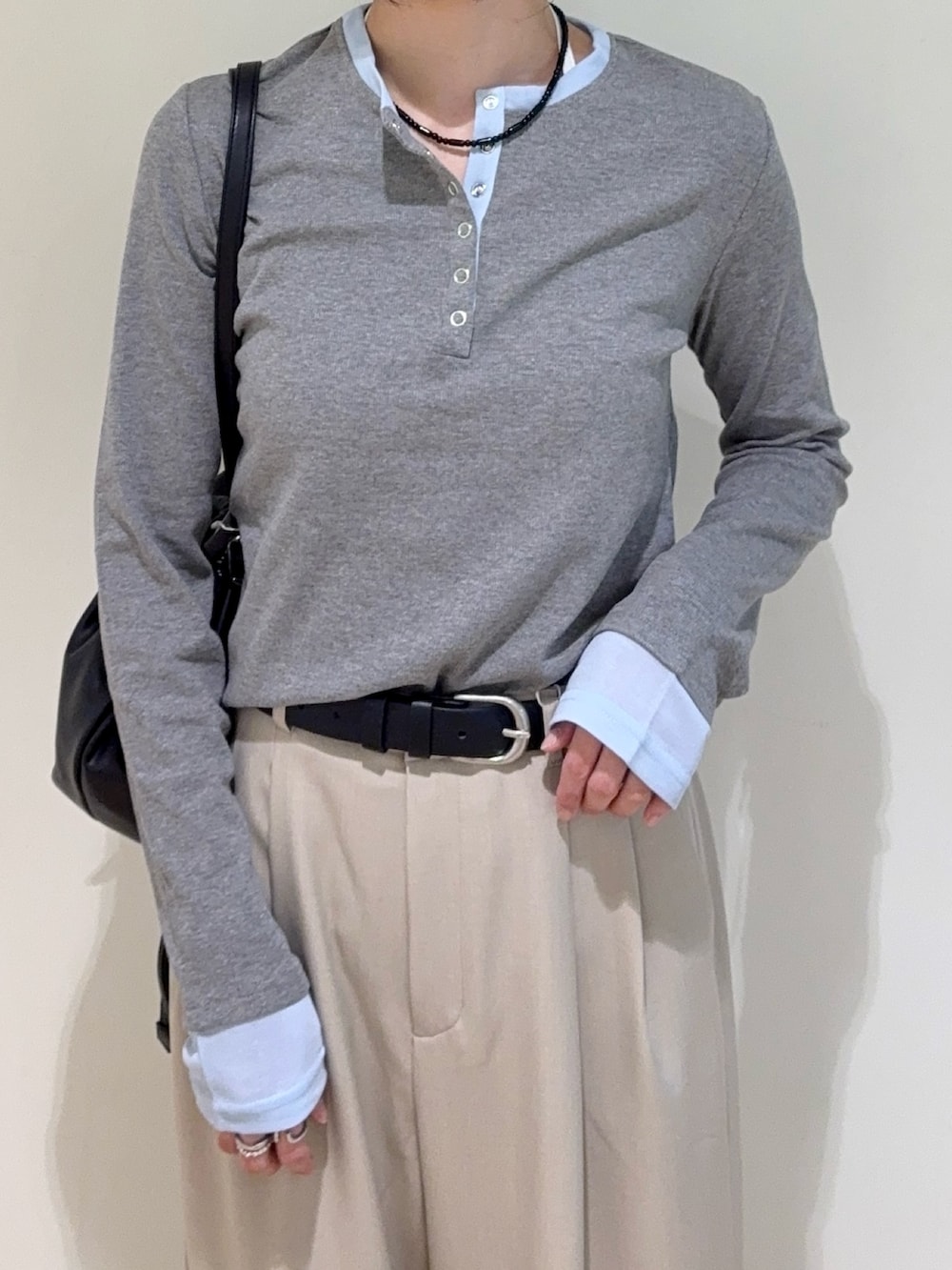 グレー系のTシャツ/カットソー、ベージュ系のスラックス、ブラック系のショルダーバッグを着用したレディースの春コーディネートの3枚目の写真