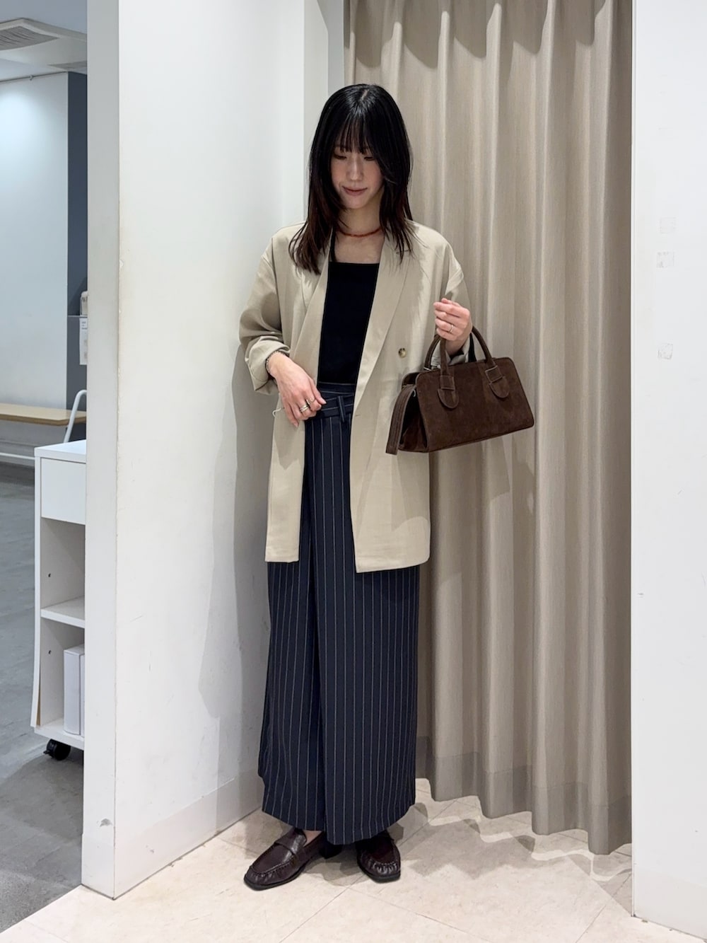 ブラック系のキャミソール、ベージュ系のその他アウター、ブラウン系のボストンバッグを着用したレディースの春コーディネートの5枚目の写真