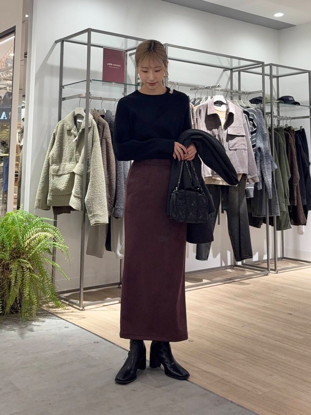 グレー系のノーカラーコート、ブラック系のブーツ、ブラック系のニット/セーターを着用したレディースの冬コーディネートの3枚目の写真