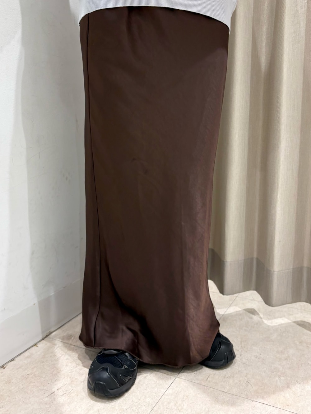 グレー系のニット/セーター、ベージュ系のハンドバッグ、ブラウン系のスカートを着用したレディースの春コーディネートの4枚目の写真