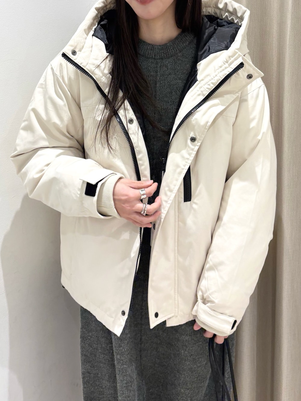 ホワイト系のダウンジャケット/コート、グレー系のワンピース、ブラック系のハンドバッグを着用したレディースの冬コーディネートの3枚目の写真