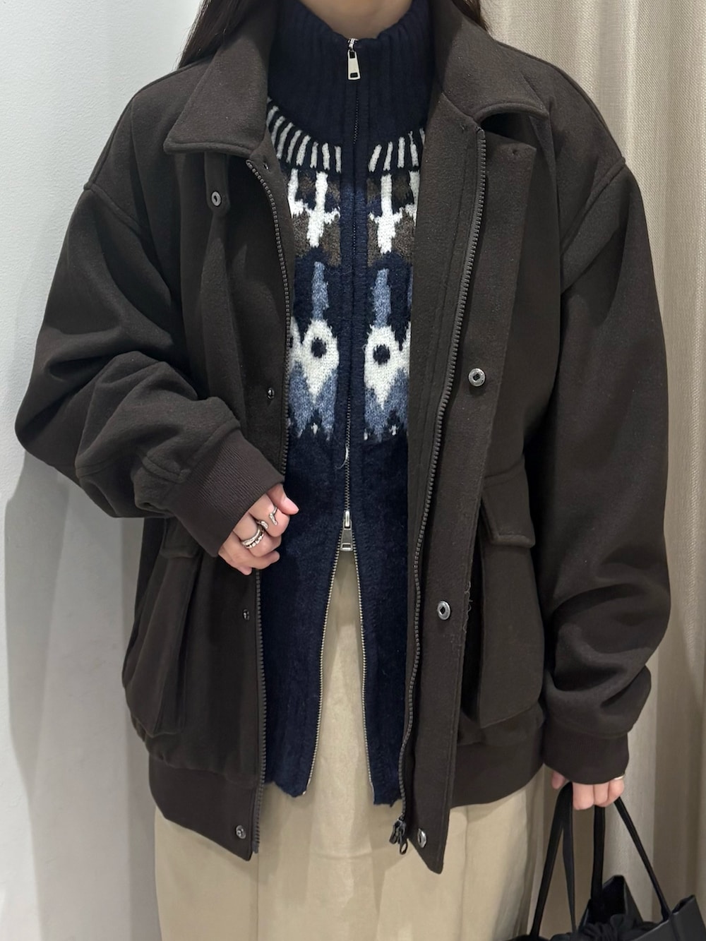 ブラウン系のブルゾン、ブルー系のニット/セーター、ベージュ系のスカートを着用したレディースの冬コーディネートの3枚目の写真