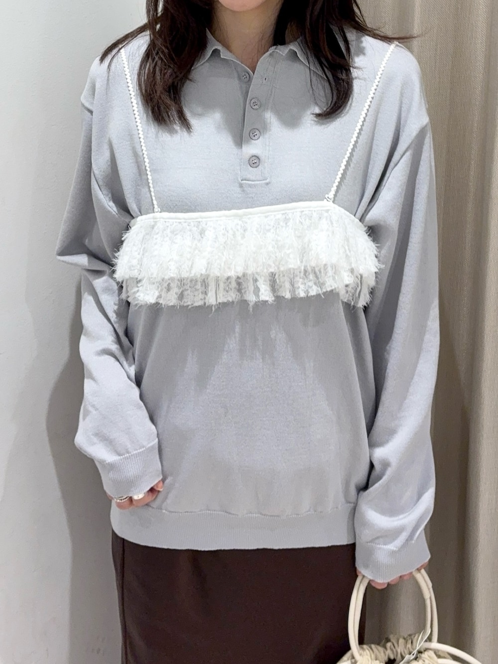 グレー系のニット/セーター、ベージュ系のハンドバッグ、ブラウン系のスカートを着用したレディースの春コーディネートの3枚目の写真