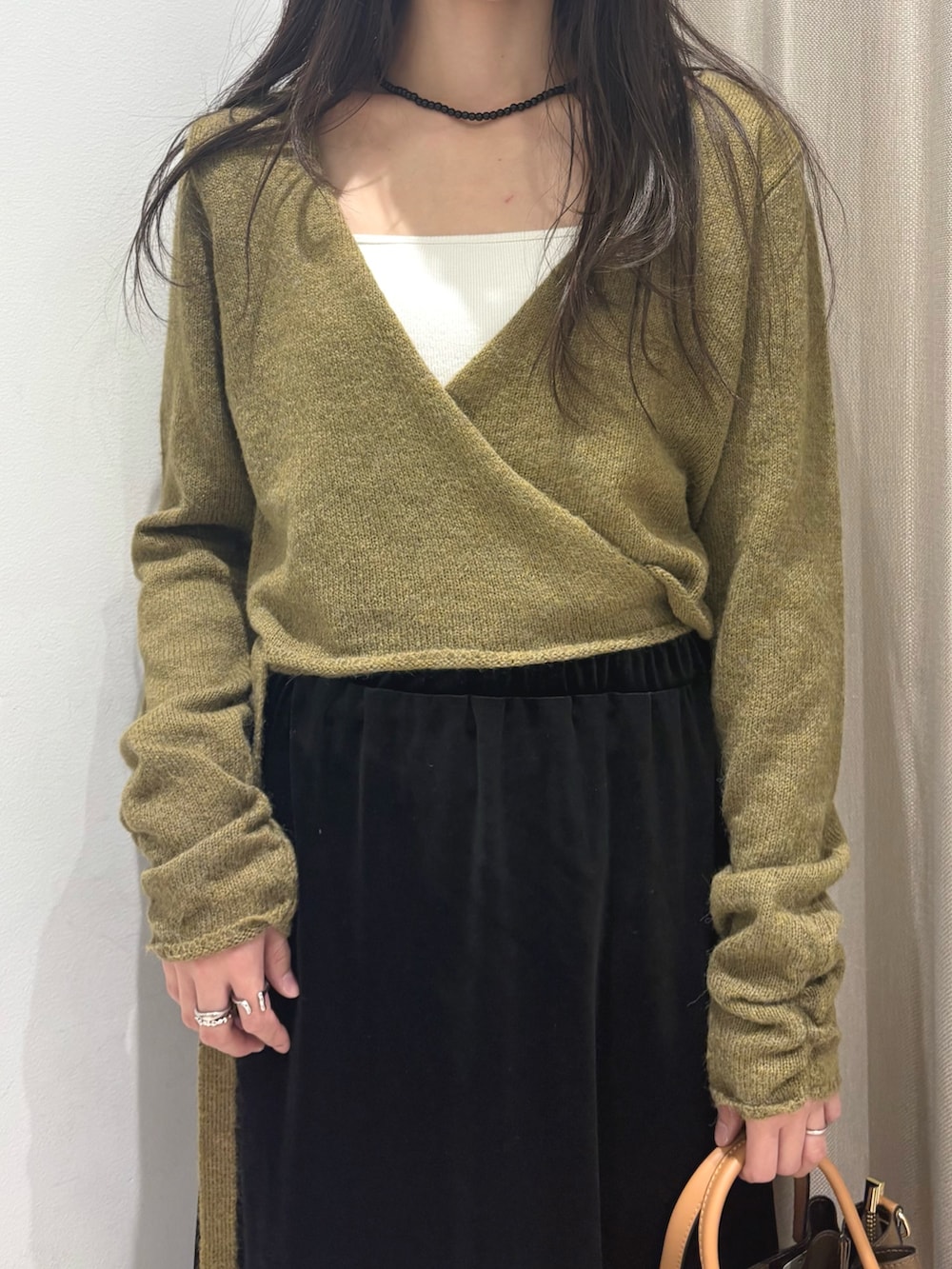 グリーン系のニット/セーター、ホワイト系のキャミソール、ブラウン系のスカートを着用したレディースの秋コーディネートの3枚目の写真