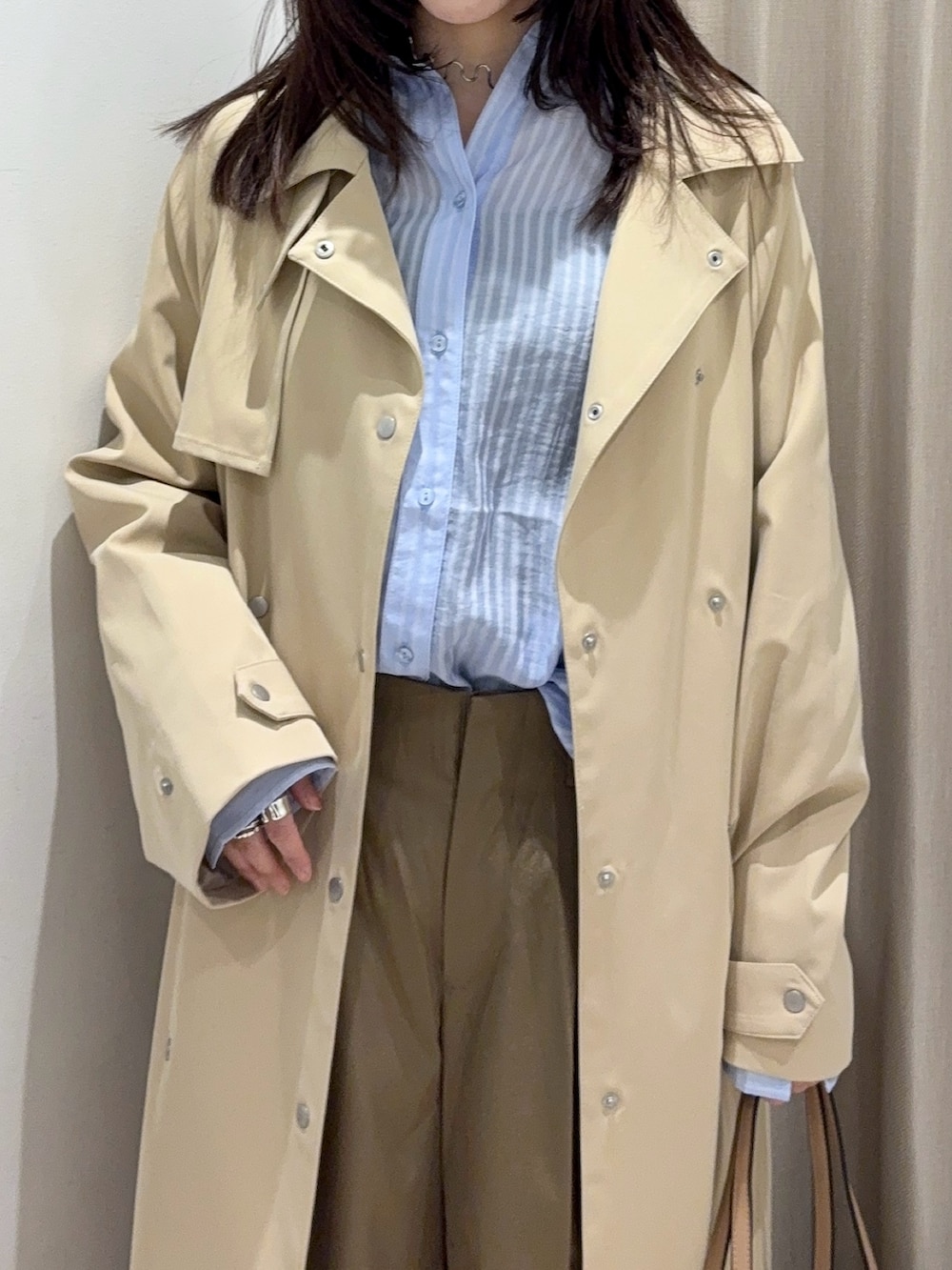 ベージュ系のチノパンツ、ブルー系のシャツ/ブラウス、ベージュ系のトレンチコートを着用したレディースの春コーディネートの2枚目の写真
