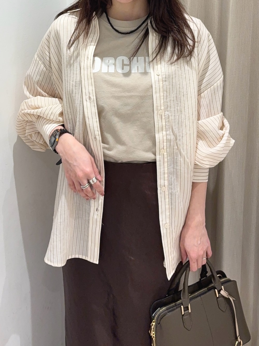 ブラウン系のスカート、ベージュ系のシャツ/ブラウス、ベージュ系のTシャツ/カットソーを着用したレディースの春コーディネートの3枚目の写真