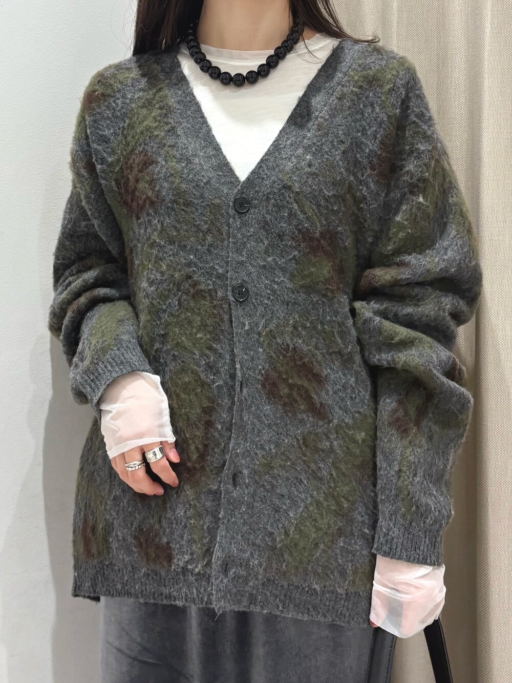グレー系のニット/セーター、ホワイト系のTシャツ/カットソー、グレー系のスカートを着用したレディースの秋コーディネートの3枚目の写真