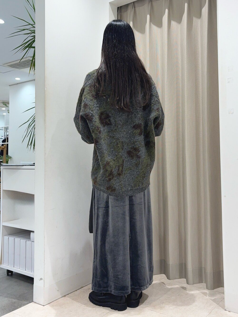 グレー系のニット/セーター、ホワイト系のTシャツ/カットソー、グレー系のスカートを着用したレディースの秋コーディネートの2枚目の写真