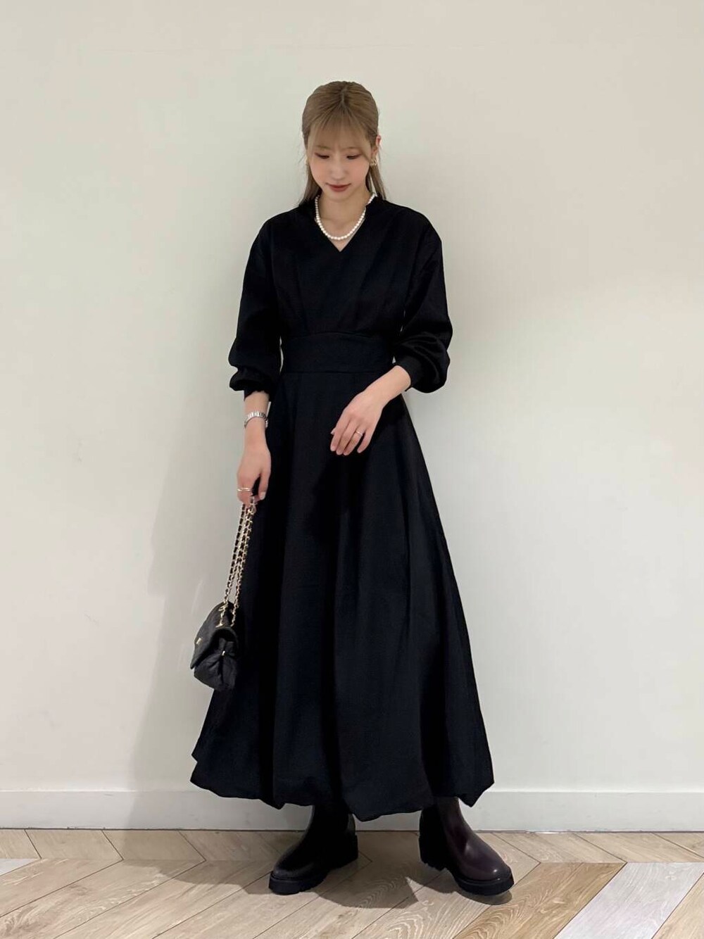 ブラック系のショルダーバッグ、ブラウン系のブーツ、ブラック系のワンピースを着用したレディースの秋コーディネートの2枚目の写真