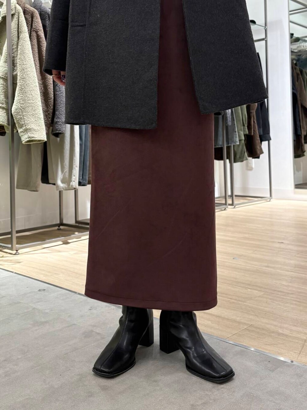 グレー系のノーカラーコート、ブラック系のブーツ、ブラック系のニット/セーターを着用したレディースの冬コーディネートの6枚目の写真