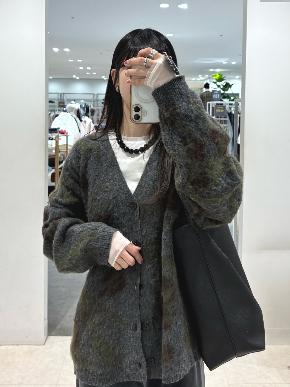 グレー系のニット/セーター、ホワイト系のTシャツ/カットソー、グレー系のスカートを着用したレディースの秋コーディネートの5枚目の写真