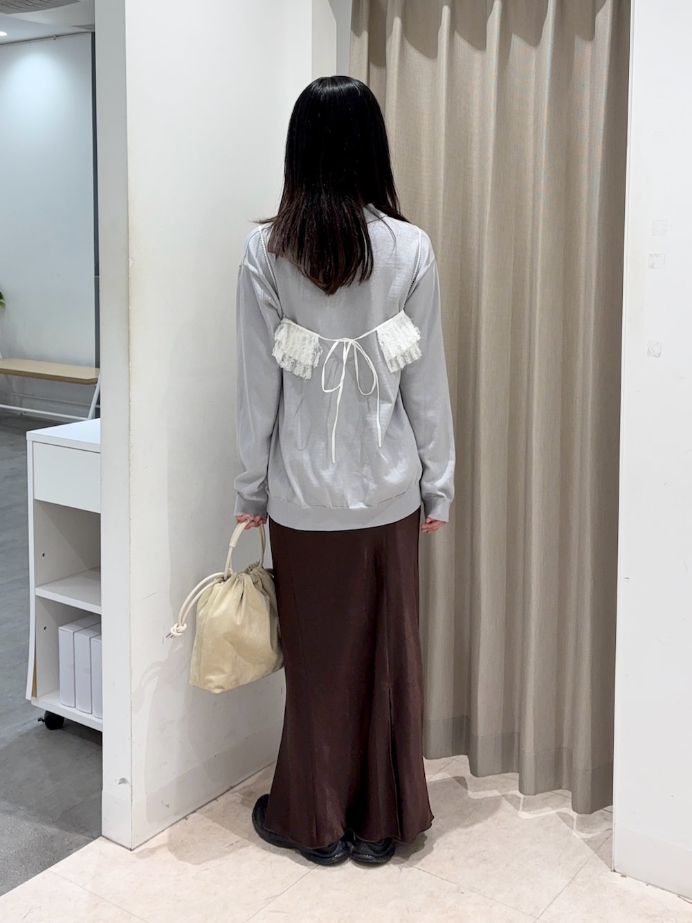 グレー系のニット/セーター、ベージュ系のハンドバッグ、ブラウン系のスカートを着用したレディースの春コーディネートの2枚目の写真