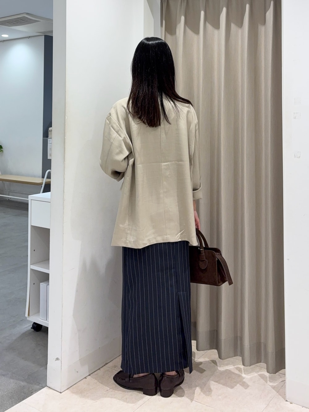 ブラック系のキャミソール、ベージュ系のその他アウター、ブラウン系のボストンバッグを着用したレディースの春コーディネートの2枚目の写真