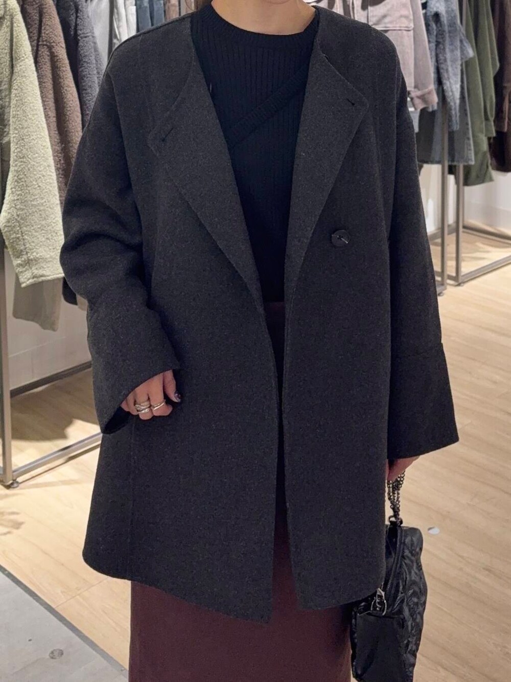 グレー系のノーカラーコート、ブラック系のブーツ、ブラック系のニット/セーターを着用したレディースの冬コーディネートの5枚目の写真