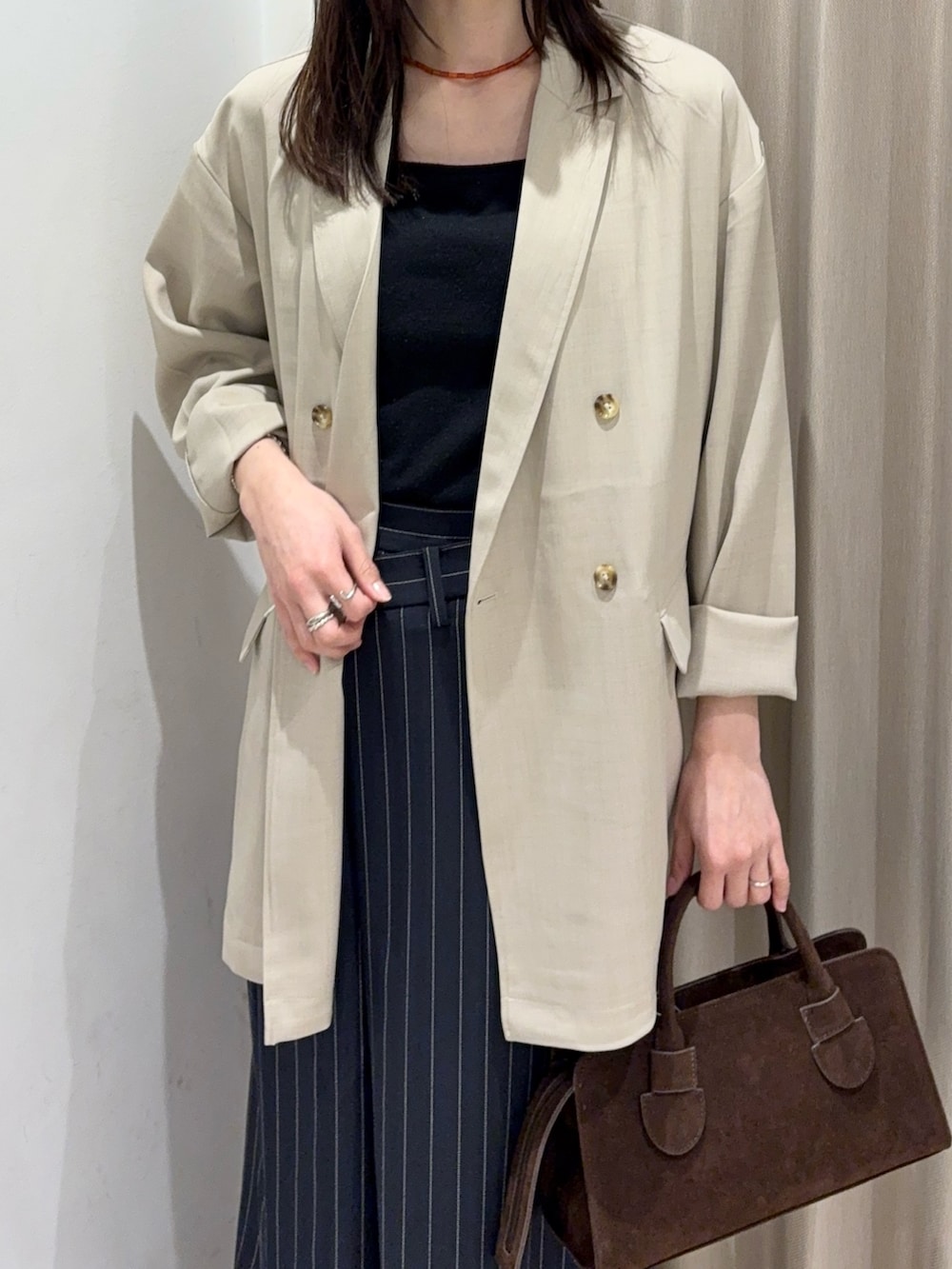 ブラック系のキャミソール、ベージュ系のその他アウター、ブラウン系のボストンバッグを着用したレディースの春コーディネートの3枚目の写真