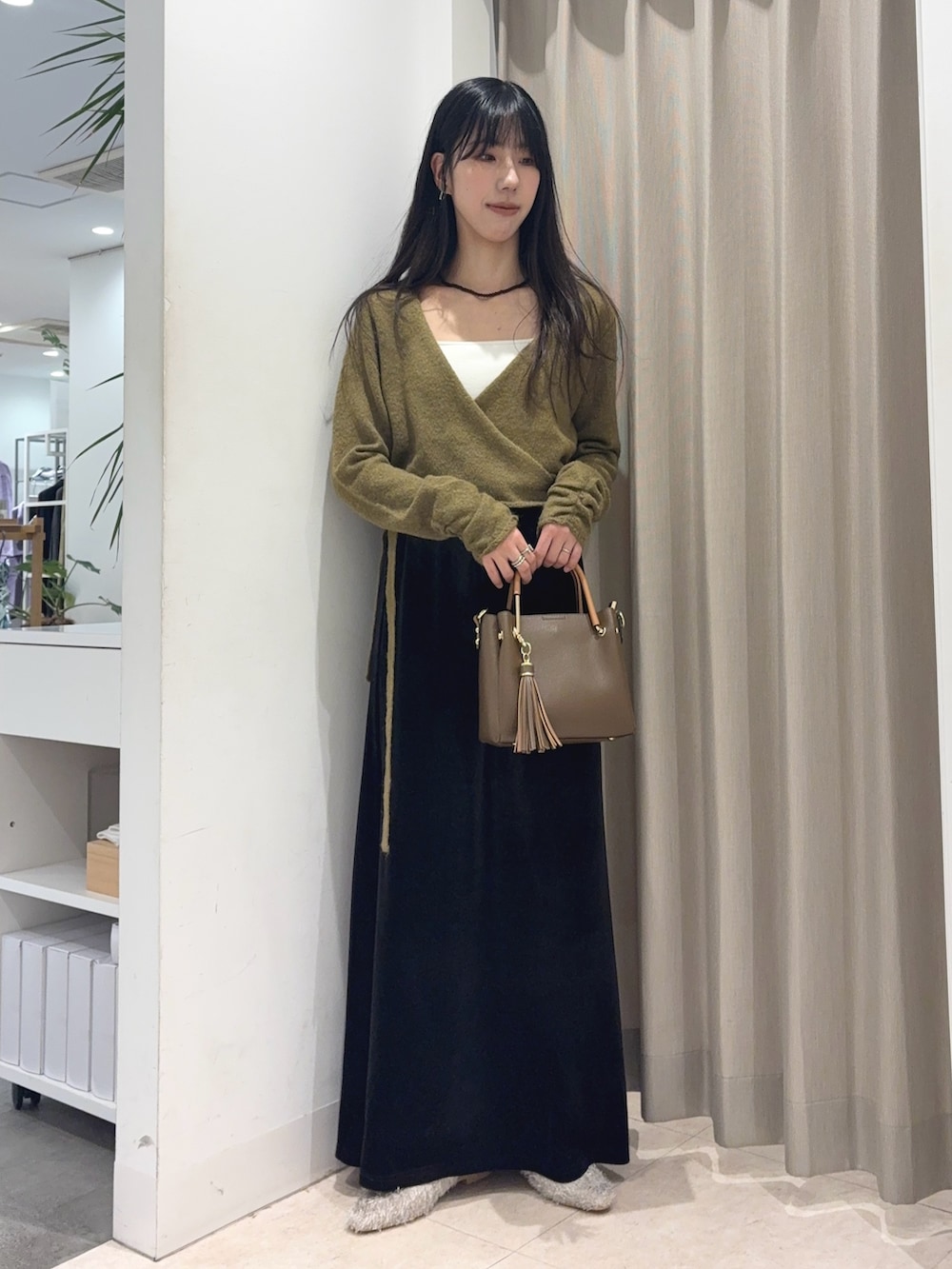 グリーン系のニット/セーター、ホワイト系のキャミソール、ブラウン系のスカートを着用したレディースの秋コーディネートの5枚目の写真