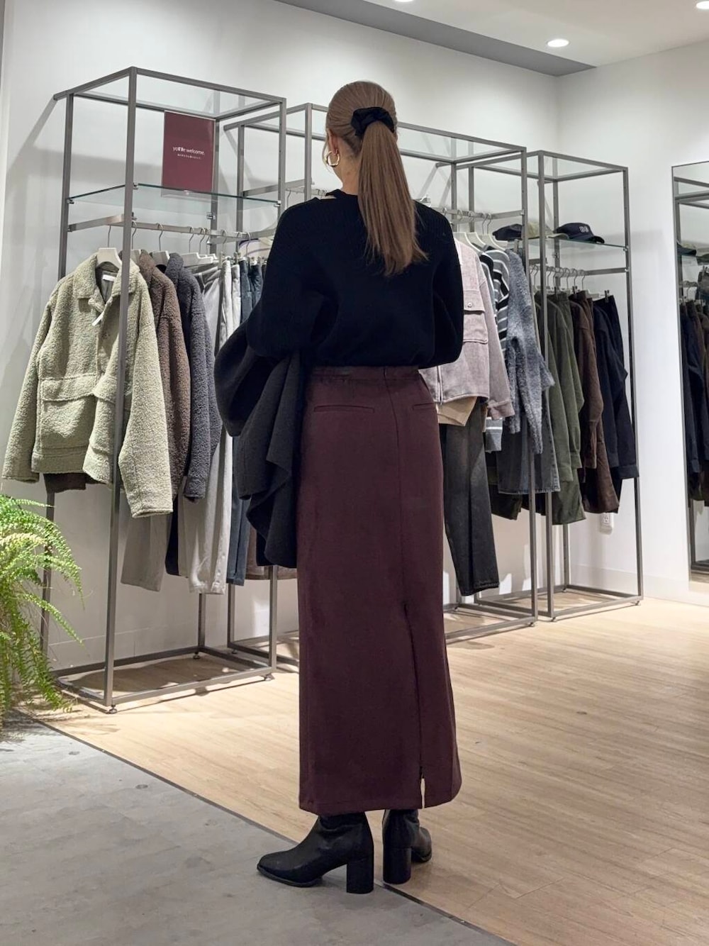 グレー系のノーカラーコート、ブラック系のブーツ、ブラック系のニット/セーターを着用したレディースの冬コーディネートの4枚目の写真